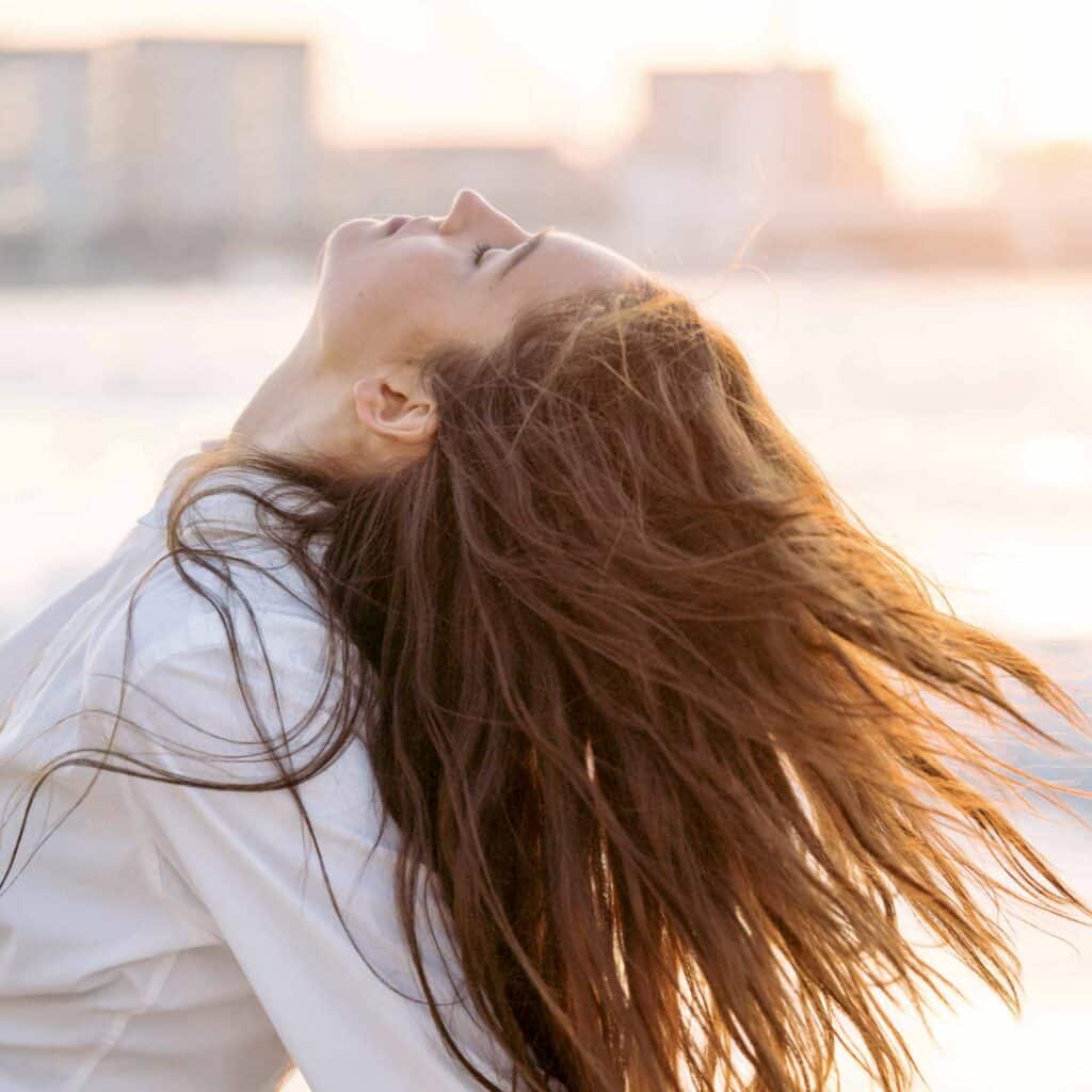 Woman flicking her hair at the beach at sunset
